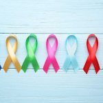 Colorful awareness ribbons on light wooden background