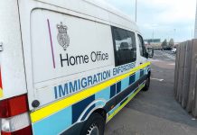 White immigration enforcement van parked by roadside near airport