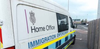 White immigration enforcement van parked by roadside near airport