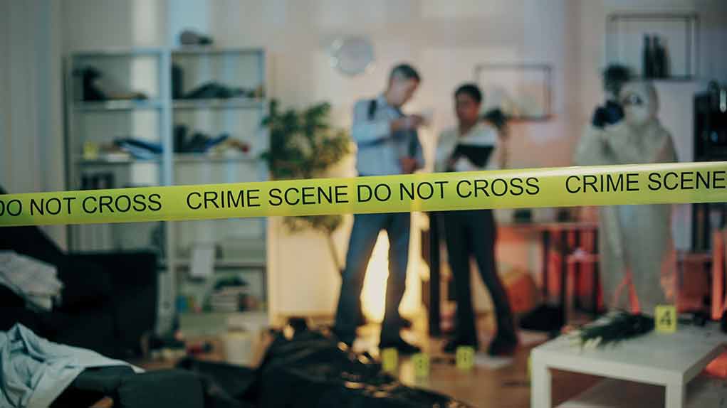 Crime scene with tape and investigators examining evidence