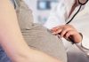 Doctor uses stethoscope on pregnant woman's belly