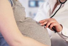 Doctor uses stethoscope on pregnant woman's belly