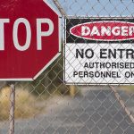Stop and Danger signs on a chain-link fence