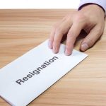 Hand holding a resignation letter on table
