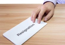 Hand holding a resignation letter on table