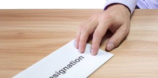 Hand holding a resignation letter on table