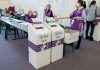 Election polling station with ballot boxes and officials