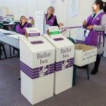 Election polling station with ballot boxes and officials