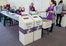Election polling station with ballot boxes and officials