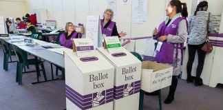 Election polling station with ballot boxes and officials