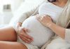 Pregnant woman holding her belly sitting comfortably