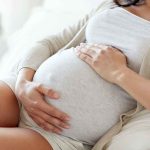 Pregnant woman holding her belly sitting comfortably