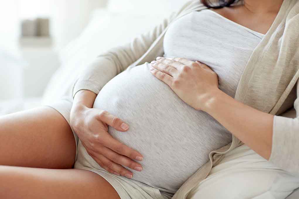 Pregnant woman holding her belly sitting comfortably