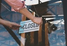 Person flipping closed sign on glass door