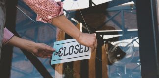 Person flipping closed sign on glass door