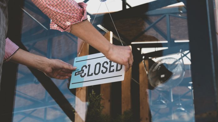 shutterstock_1162554778.jpg featured image Person flipping closed sign on glass door