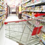 Empty shopping cart in grocery store aisle.