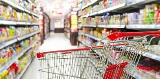 Empty shopping cart in grocery store aisle.