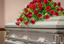 Silver casket with red rose arrangement on top.