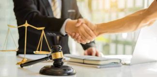 Hands shaking over legal documents with gavel and scales
