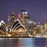 Sydney Opera House at night with city skyline.
