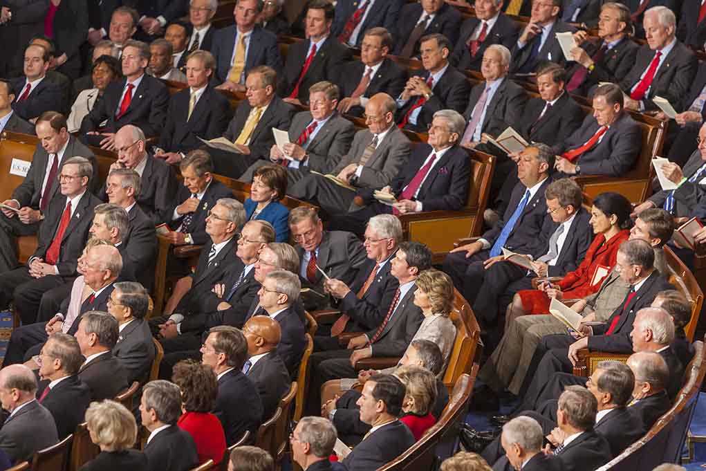 Audience of officials sitting and reading documents in auditorium