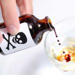 Person pouring liquid from poison bottle into glass
