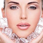 Close up of a woman holding ice cubes around her face