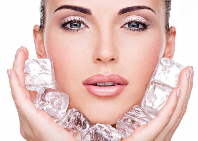 shutterstock_163387733.jpg Close up of a woman holding ice cubes around her face