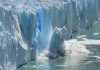 A glacier calving into the ocean creating a splash of ice and water
