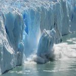 A glacier calving into the ocean creating a splash of ice and water