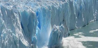 A glacier calving into the ocean creating a splash of ice and water