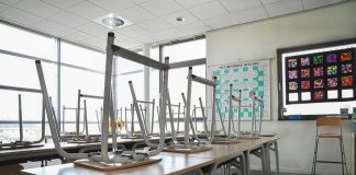 Empty classroom with chairs on top of desks