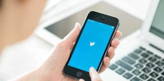 Person holding a smartphone displaying the Twitter app