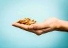 A hand holding a stack of gold coins against a light blue background
