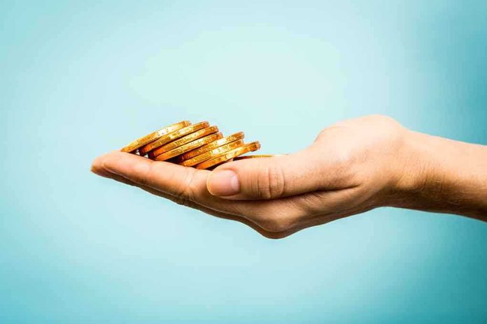 A hand holding a stack of gold coins against a light blue background