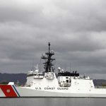 A US Coast Guard ship docked under cloudy skies