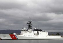 A US Coast Guard ship docked under cloudy skies