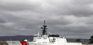 A US Coast Guard ship docked under cloudy skies