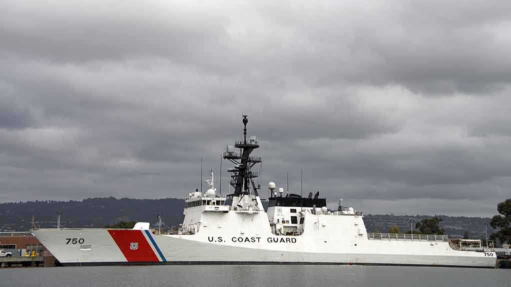 A US Coast Guard ship docked under cloudy skies