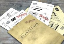 Classified documents with Top Secret stamps on wooden surface.