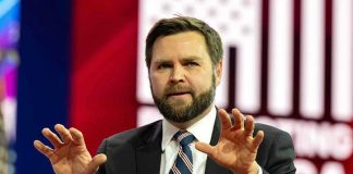 Man in suit gesturing with hands on stage