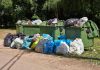 Overflowing garbage bins with bags on the ground.