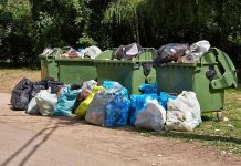 Overflowing garbage bins with bags on the ground.