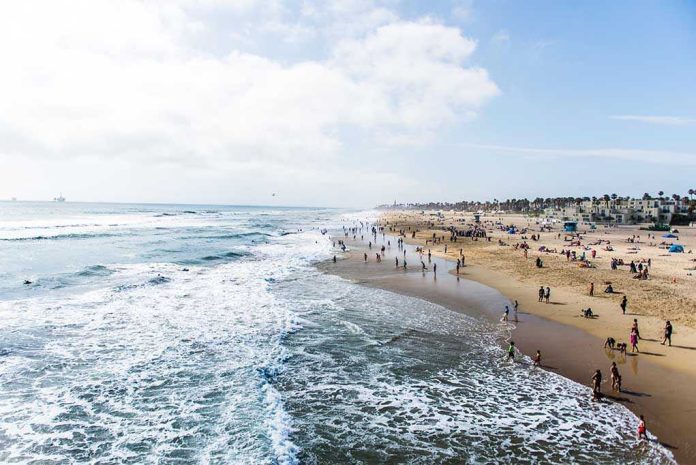 697274677 Crowded beach with waves and people enjoying sun.
