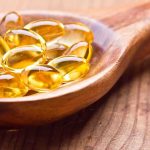 Golden omega3 capsules in a wooden spoon