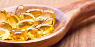 Golden omega3 capsules in a wooden spoon