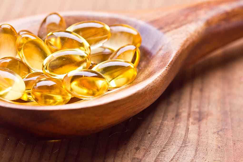 Golden omega3 capsules in a wooden spoon