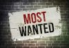 A weathered poster displaying the words MOST WANTED on a brick wall