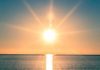 A serene sunrise over a calm ocean with vibrant colors in the sky